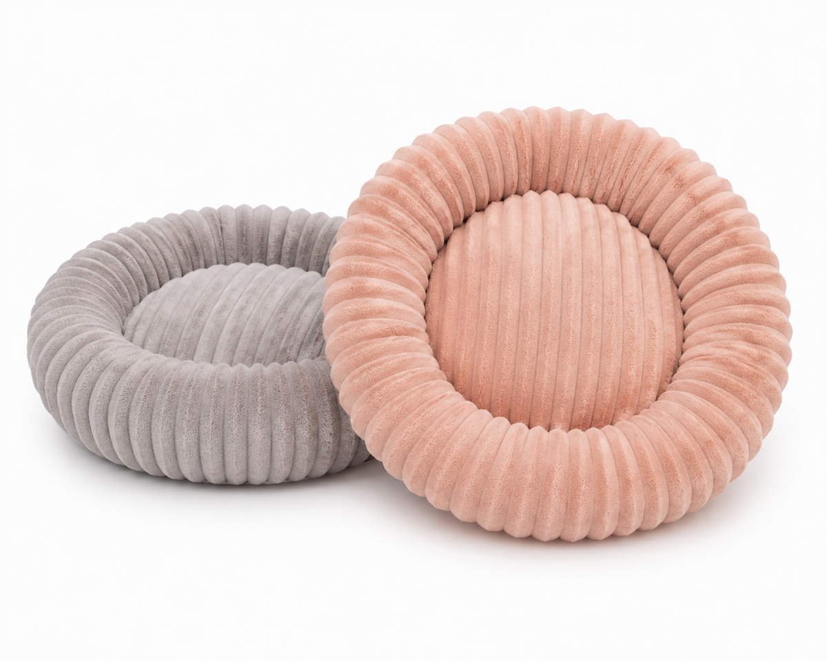 Two round ribbed pet beds on a white background, one in light gray and one in dusty pink.